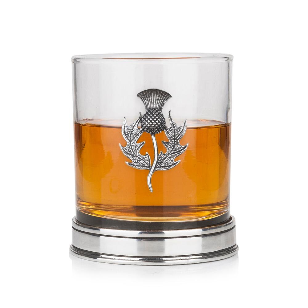 Whisky tumbler with pewter thistle motif and polished base, partially filled with amber liquid
